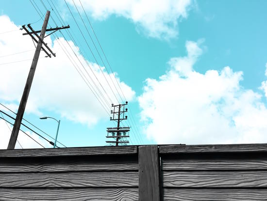 electric pole with wooden wall and blue cloudy sky in the city by Timmy333