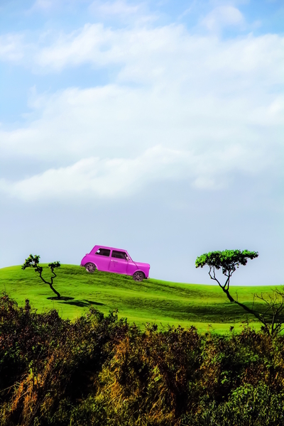 pink classic car on the green mountain with cloudy blue sky by Timmy333