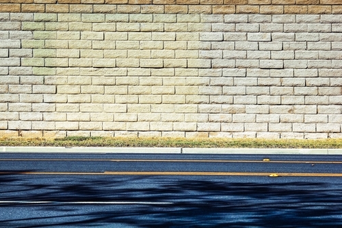 road with shadows and brick wall background Mural by Timmy333